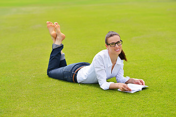 Image showing Young woman reading a book in the park