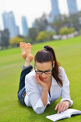 Image showing Young woman reading a book in the park