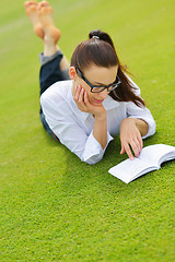 Image showing Young woman reading a book in the park