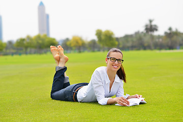 Image showing Young woman reading a book in the park