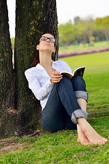 Image showing Young woman reading a book in the park