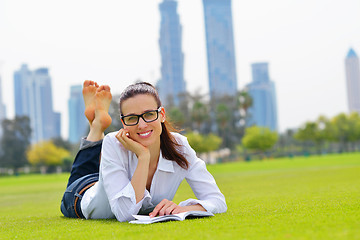 Image showing Young woman reading a book in the park