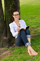 Image showing Young woman reading a book in the park