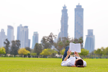 Image showing Young woman reading a book in the park