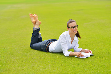 Image showing Young woman reading a book in the park