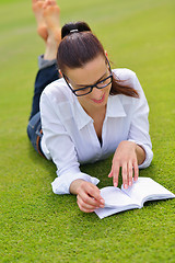 Image showing Young woman reading a book in the park