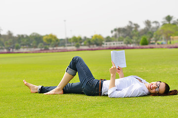 Image showing Young woman reading a book in the park