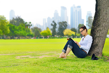 Image showing Young woman reading a book in the park