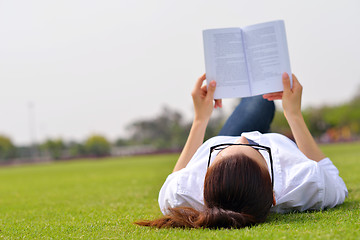 Image showing Young woman reading a book in the park