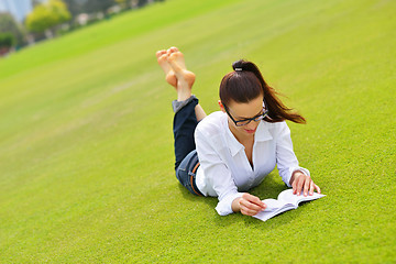 Image showing Young woman reading a book in the park