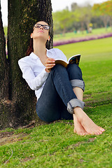 Image showing Young woman reading a book in the park