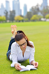 Image showing Young woman reading a book in the park