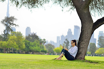 Image showing Beautiful young woman with  tablet in park