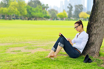 Image showing Young woman reading a book in the park