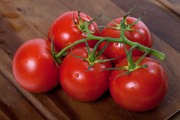 Image showing Bunch of fresh tomatoes with water drops on wooden table