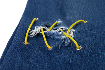 Image showing Blue jean with hole and crisscross yellow lacing