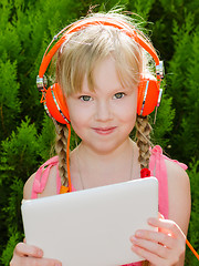 Image showing Cute girl with tablet pc listening music in headphones