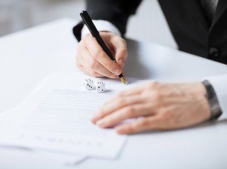 Image showing man hands with gambling dices signing contract