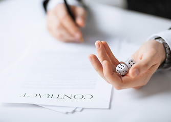 Image showing man hands with gambling dices signing contract