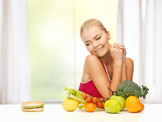 Image showing doubting woman with fruits and hamburger