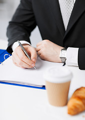 Image showing businessman with coffee writing something