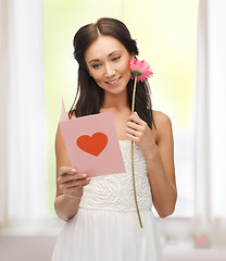 Image showing young woman holding flower and postcard