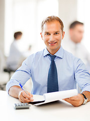 Image showing businessman with notebook and calculator in office