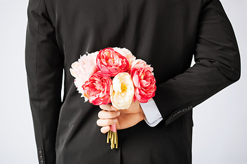 Image showing man hiding bouquet of flowers