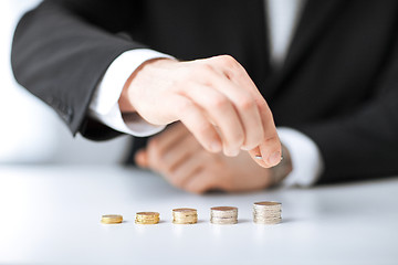 Image showing man putting stack of coins into one row