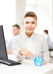 Image showing businesswoman pointing at clock in office