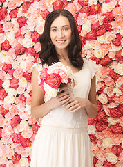 Image showing woman with bouquet and background full of roses