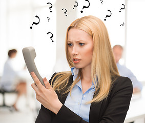 Image showing confused woman with phone in office