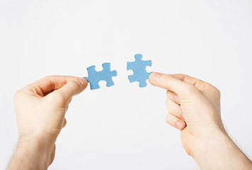 Image showing two hands trying to connect puzzle pieces