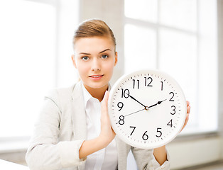 Image showing attractive businesswoman showing white clock