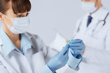 Image showing female doctor holding syringe with injection