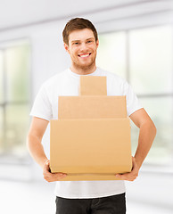 Image showing smiling man carrying carton boxes at home