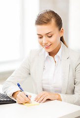 Image showing businesswoman writing on sticky note