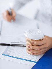 Image showing woman filling in form and drinking coffee