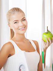 Image showing sporty woman with scale, apple and measuring tape