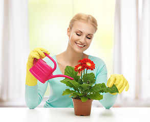 Image showing housewife with flower in pot and watering can