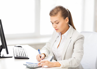 Image showing businesswoman with notebook and calculator