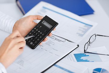 Image showing woman hand with calculator and papers