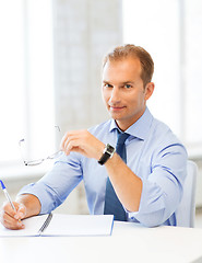 Image showing businessman with spectacles writing in notebook