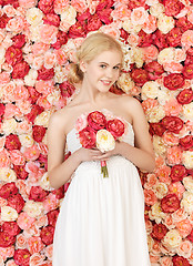 Image showing woman with bouquet and background full of roses