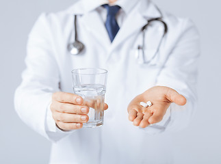 Image showing doctor hands giving white pills and glass of water