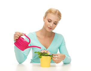 Image showing housewife with flower in pot and watering can