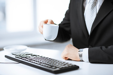 Image showing man hands with keyboard drinking coffee