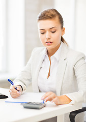 Image showing businesswoman with notebook and calculator