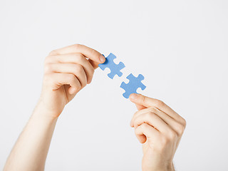 Image showing two hands trying to connect puzzle pieces