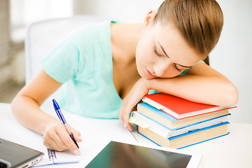 Image showing tired student sleeping on stock of books